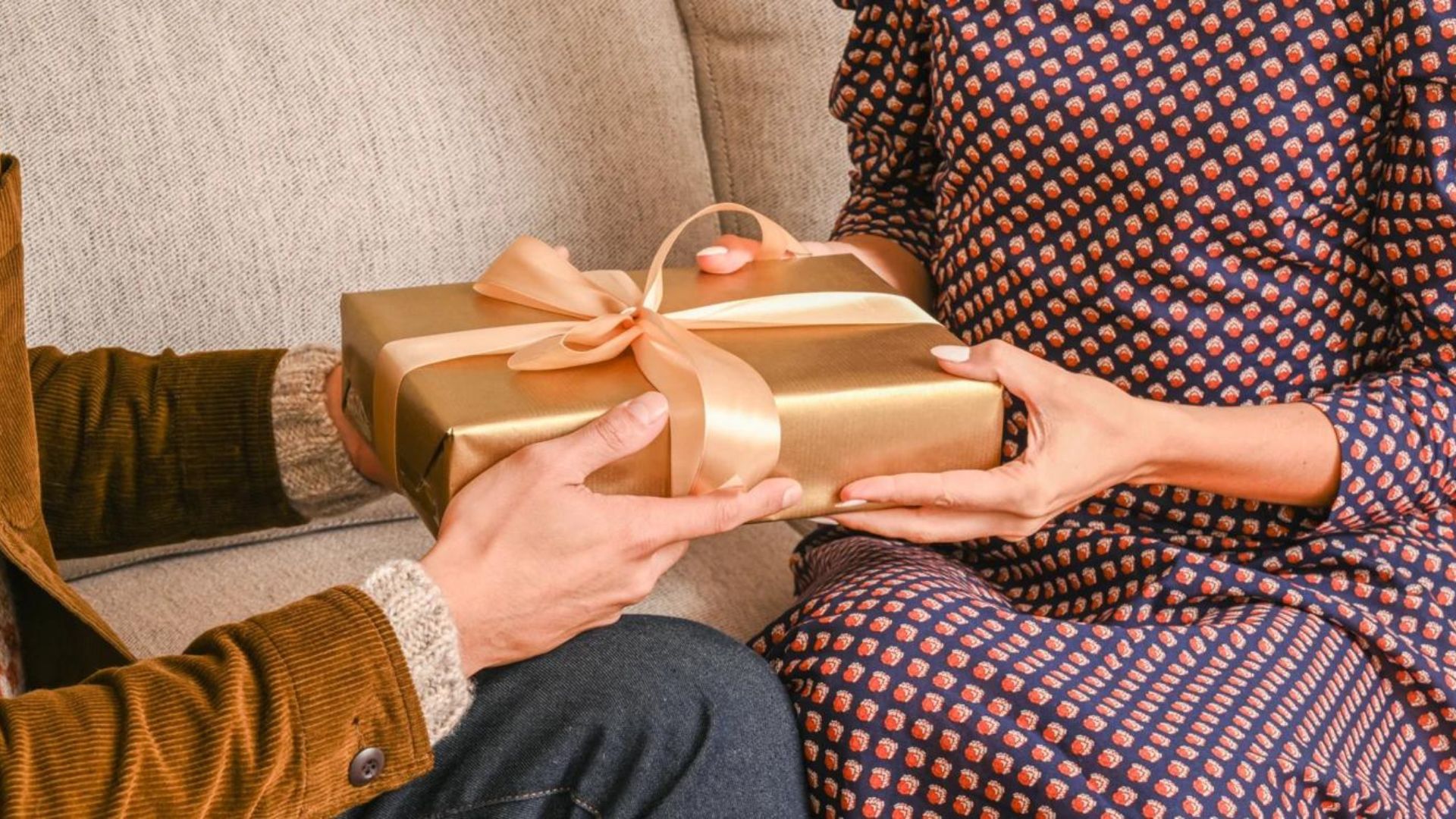 a man and a woman sitting while holding a box of a gift showing the best gift to give someone 